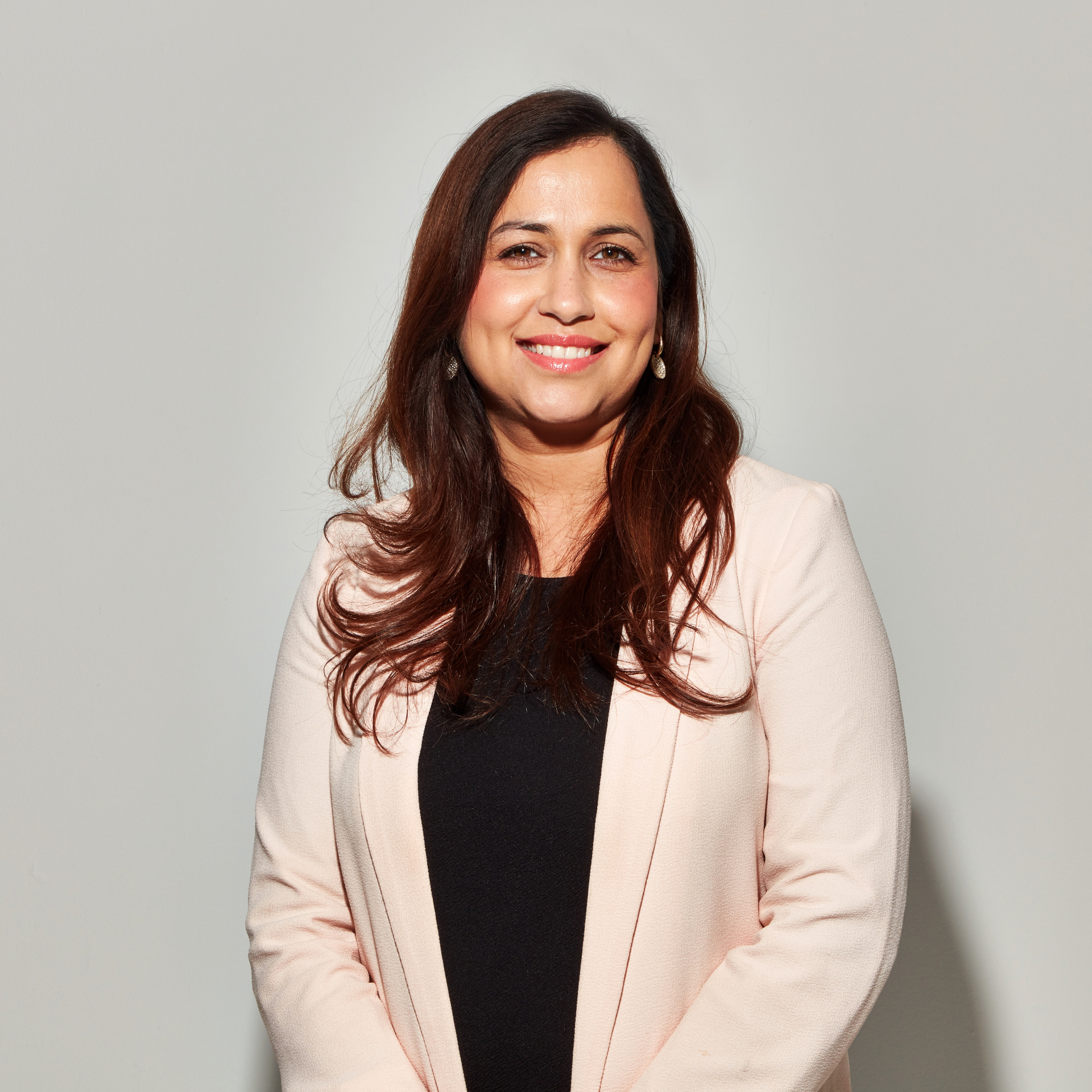 Poonam Pahwa, founder of RASA, smiling in a soft pink blazer